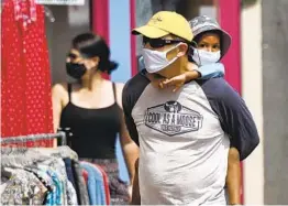  ?? ROBERT F. BUKATY AP ?? Shoppers walk by storefront­s while wearing masks to protect against the coronaviru­s Saturday in Bath, Maine.