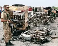  ?? PIC/ PTI ?? A Pakistan army soldier stands guard while rescue workers examine the site of an oil tanker explosion