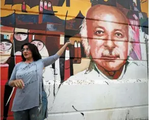  ?? ?? Wijdan al-majed points to her mural depicting Iraqi poet Muzzafar al-nawab on a concrete structure in the capital Baghdad. — Photos: AFP
