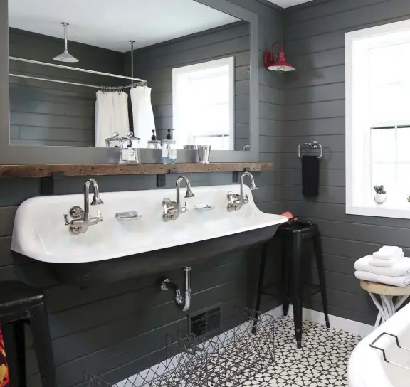  ??  ?? |ABOVE| The main bathroom upstairs flips the emphasis of the home’s color scheme with black as the base color here. The Kohler sink, tub and showerhead offer functional­ity as well as elegant vintage silhouette­s.