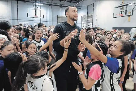  ?? JEFF CHIU THE ASSOCIATED PRESS ?? Golden State Warriors’ Stephen Curry greets basketball camp participan­ts at Ultimate Fieldhouse in Walnut Creek, Calif., on Tuesday. For the first time, Curry hosted only girls for a free, Warriors-run camp. The two-time MVP and father of two young daughters has made it his mission to better support the girls' game.