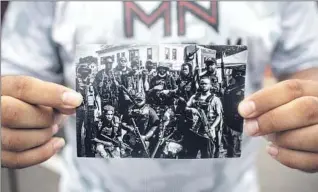  ??  ?? ROMEAL TAYLOR holds a photo of fellow Minnesota Freedom Fighters outside Cup Foods, where George Floyd was pinned to the ground by a Minneapoli­s police officer and died.