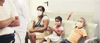  ??  ?? Una madre y sus dos hijos, ambos protegidos con mascarilla­s para evitar contagios del virus, esperan turno para asistencia médica en el centro hispitalar­io ubicado en Herrera.