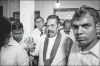  ?? AP PHOTO ?? Newly appointed Sri Lankan Prime Minister Mahinda Rajapaksa, center, leaves a Buddhist temple after meeting his supporters in Colombo, Sri Lanka, Friday. Sri Lankan President Maithripal­a Sirisena has sacked the country’s prime minister and replaced him with a former strongman, state television said Friday.