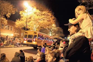  ?? Photos by Spencer Lahr, Rome News-Tribune ?? ABOVE: Mike Heneghan holds his daughter Leighton Heneghan, 4, on his shoulders while his older daughter Isabella Heneghan stands in front of him on a sidewalk of Broad Street during the Rome Christmas Parade.