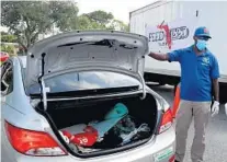  ?? MIKE STOCKER/SOUTH FLORIDA SUN SENTINEL ?? School security officer Cedric Golden on Wednesday assists Oceans 234 in distributi­ng free meals to schoolchil­dren and their families at Orange Brook Elementary School in Hollywood.