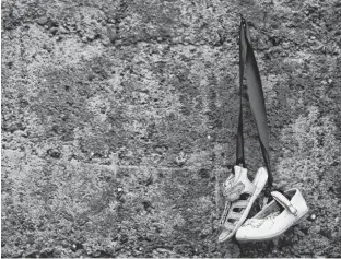  ?? REUTERS ?? Baby shoes hang from a wall on Tuesday at a graveyard where the bodies of 796 babies were uncovered at the site of a former Catholic home for unmarried mothers and their children in Tuam, Ireland.