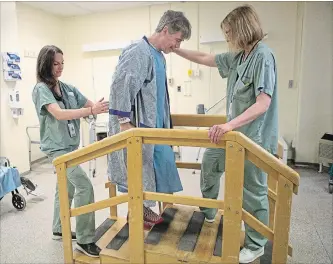  ?? CHRIS YOUNG THE CANADIAN PRESS ?? Physiother­apist Ellen Newbold, right, and occupation­al therapist Mary Van Impe help Tim Heenan walk up some steps as he prepares for his release following day surgery for a hip replacemen­t at St. Michael's Hospital in Toronto.