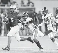  ??  ?? St. Thomas Aquinas’ Daniel Carter sprints ahead of several Lakeland defenders in the 7A state final game.