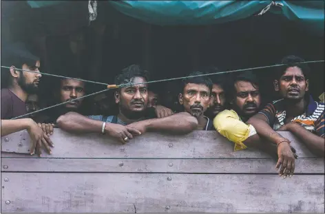  ?? (AP/Binsar Bakkara) ?? Men from Bangladesh ride in the back of a truck heading to an immigratio­n detention center in Medan, North Sumatra, Indonesia. Officials said a few dozen men were found locked in a house, waiting for a broker to bring them illegally by boat to Malaysia, with some planning to work on palm oil plantation­s.