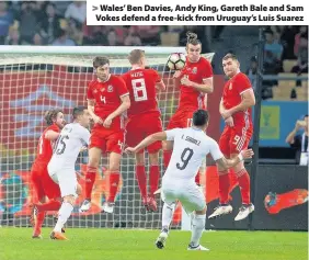  ??  ?? > Wales’ Ben Davies, Andy King, Gareth Bale and Sam Vokes defend a free-kick from Uruguay’s Luis Suarez