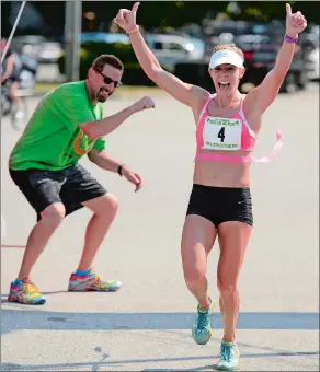  ?? SEAN D. ELLIOT/THE DAY ?? Way Hedding, left, releases the tape as women’s winner Sybil Shapiro crosses the finish line of the 53rd Annual Ocean Beach/John & Jessie Kelley Road Race on Aug. 1, 2015.