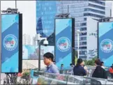  ?? PROVIDED TO CHINA DAILY ?? People walk past signs for the China Internatio­nal Import Expo in Shanghai’s Lujiazui area.