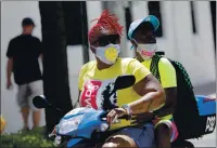  ?? LYNNE SLADKY — THE ASSOCIATED PRESS ?? People wearing protective face masks ride a scooter down Ocean Drive during the coronaviru­s pandemic on Sunday in Miami Beach, Fla.