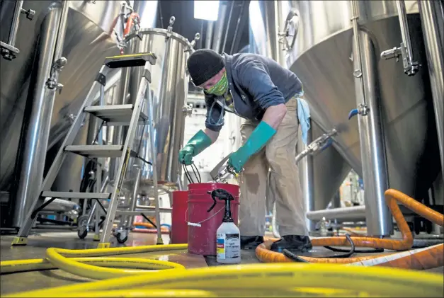  ?? Timothy Hurst / Staff Photograph­er ?? Cellar operator Zack Lawrence cleans and sanitizes parts of the brewery’s dry hop tank on Tuesday at Upslope Brewing in Boulder. Upslope is one of 54 certified B Corporatio­ns in Boulder County.