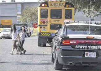  ??  ?? Elementary school students wave to DPS trooper Mark Brimberry as they cross the street in North Austin on Thursday. Last year state troopers handed out more than 1,000 citations for passing a stopped bus. Cook Warren