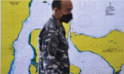  ?? Photograph: Antara Foto/ Reuters ?? A member of the Indonesian navy walks past a map of the search area for the KRI Nanggala-402 submarine.