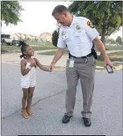  ?? STAFF PHOTO BY ANDREW RICHARDSON ?? Maj. Chris Becker with Skylah Brown, 4, as they celebrate National Night Out at the Sheffield neighborho­od.