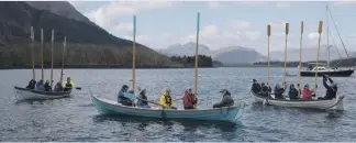  ?? Photograph: Iain Ferguson, alba.photos ?? Crews of the three visiting skiffs raise their oars in salute to the Corrag.