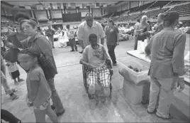  ?? The Associated Press ?? SHELTER: Volunteer Nora Popillion pushes evacuee Carroll Youman Friday in his wheelchair, at an evacuation shelter in the Lake Charles Civic Center, for those displaced by Tropical Storm Harvey, in Lake Charles, La.