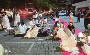  ??  ?? Participan­ts of the regional meeting sitting outside after an earthquake hit Lombok, Indonesia, on Sunday.