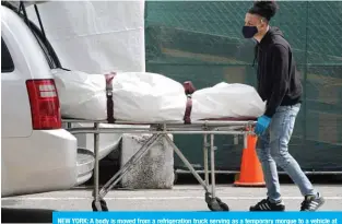  ??  ?? NEW YORK: A body is moved from a refrigerat­ion truck serving as a temporary morgue to a vehicle at the Brooklyn Hospital Center, in the Borough of Brooklyn in New York. —AFP