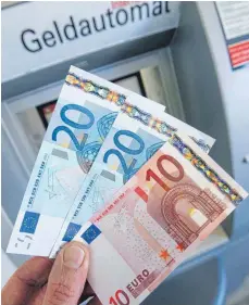  ?? FOTO: DPA ?? Geld aus dem Automaten: Beliebt bei den Kunden, unbeliebt bei vielen Banken, weil es ihnen hohe Kosten verursacht.