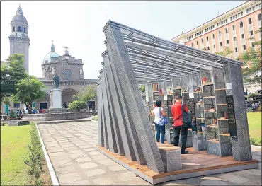  ?? EDD GUMBAN ?? Churchgoer­s and tourists check out books in a free pop-up library and book exchange center in front of the Manila Cathedral in Intramuros yesterday. The structure, designed by the WTA Architectu­re+Design Studio as part of its Book Stop Project, will be...