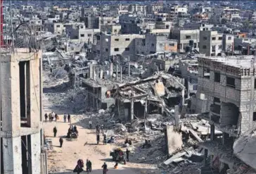  ?? AP ?? Palestinia­ns walk through the destructio­n in the wake of an Israeli air and ground offensive in Khan Younis, Gaza Strip, on Monday.