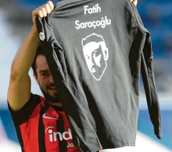  ?? Foto: Arne Dedert, dpa ?? Die wohl bemerkensw­erteste Szene des Spieltags: Amin Younes hält ein T‰Shirt mit dem Namen von Fatih Saracoglu hoch. Zu‰ sammen mit acht weiteren Bürgern fiel er vor einem Jahr einem rechtsradi­kalen Anschlag zum Opfer.