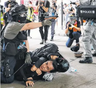  ?? TYRONE SIU REUTERS ■ ?? A police officer raises his pepper spray handgun as he detains a man during a march against the national security law at the anniversar­y of Hong Kong’s handover to China from Britain in Hong Kong, China, Wednesday.