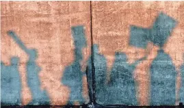  ?? AP ?? The sun casts shadows of union protesters on a wall as they march in front of an entrance to a port in Washington state in 2011 in an effort to stop grain from being shipped overseas.