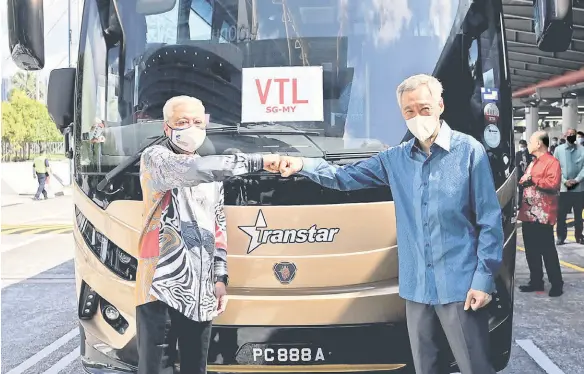  ?? — Bernama photo ?? Ismail Sabri (left ) and Lee bump fists to symbolise the launching of the land Vaccinated Travel Lane at the Woodlands checkpoint.