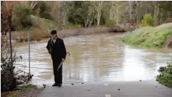  ??  ?? CALIFORNIA: Dennis Rogers stands next to a flooded trail along Los Gatos Creek after a series of storms in Los Gatos, California. —AP