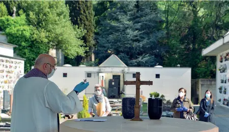  ??  ?? Scanzorosc­iate Ogni 15 minuti, un’urna: nel cimitero i parenti si sistemano a distanza e un sacerdote dà la benedizion­e (Ansa/Manzoni)