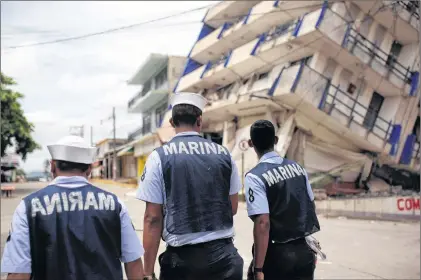  ?? AP PHOTO ?? Three Navy sailors walk by the partially collapsed structure of a hotel in the town of Matias Romero, Oaxaca state, Mexico, Friday.