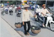  ?? AFP ?? A migrant worker carries collected items for recycling along a road in downtown Hanoi on Sept 10.