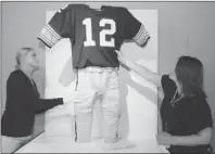  ?? Bob Donaldson/post-gazette ?? Heinz History Center’s Courtney Keel, left, and Paula Andras smooth the wrinkles out of Terry Bradshaw’s 1970s uniform as the NFL Hall of Fame exhibit nears completion. The exhibit opens Saturday.