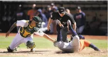  ?? Ezra Shaw / Getty Images ?? Houston’s George Springer slides safely past A’s catcher Bruce Maxwell in the seventh inning at the Coliseum.