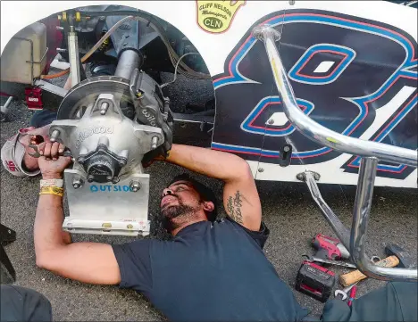  ?? SARAH GORDON/THE DAY ?? Crew members Nick Beaver, front, and Dan Wilson work on squaring up the rear end tires on the SK Light Modified car driven by Brett Gonyaw prior to Saturday’s feature race on opening day at the New London-Waterford Speedbowl. Gonyaw went on to win the...