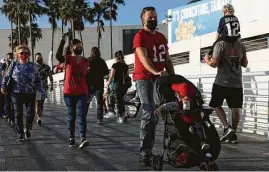  ?? Eve Edelheit / New York Times ?? Football fans wear protective face masks as they walk along the Hillsborou­gh River ahead of the Super Bowl in Tampa, Fla.