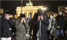  ?? MARKUS SCHREIBER AP ?? People mourn Thursday in front of the Brandenbur­g Gate near the French embassy in Berlin, at a commemorat­ion for the victims killed in a church attack in Nice, France.