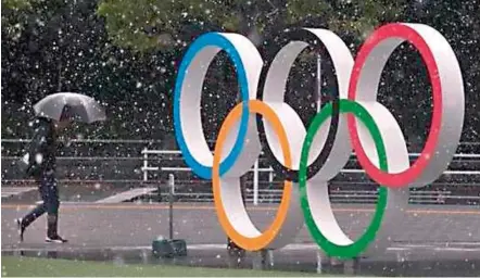  ??  ?? A man walks past giant Olympic rings near the new National Stadium in Tokyo last Saturday.