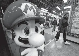  ?? Shizuo Kambayashi / Associated Press ?? A Super Mario figure greets shoppers at an electronic­s store in Tokyo. Nintendo is exploring different ways of charging people for games, “Super Mario” creator Shigeru Miyamoto says.