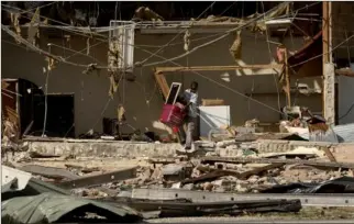  ?? JONATHAN BACHMAN / REUTERS ?? 13-year-old Kaleb Cassel removes belongings from a flea market damaged by Hurricane Michael in Panama City, Florida on Thursday.