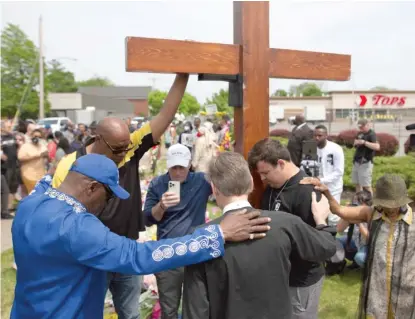  ?? JOSHUA BESSEX/AP ?? A group prays on Saturday for those who were killed and wounded May 14 at a Tops Friendly Market in Buffalo, N.Y.