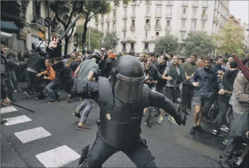  ?? PICTURE: AP PHOTO/MANU FERNANDEZ. ?? POLL FLASHPOINT: A spanish riot police swings a club against would-be voters near a school assigned as a polling station in Barcelona.