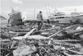  ?? Antonio Calanni / Associated Press ?? People clean up debris after a storm struck Rapallo, northern Italy. Two days of rain and wind ravaged Italy, and St. Mark’s Basilica in Venice was damaged.