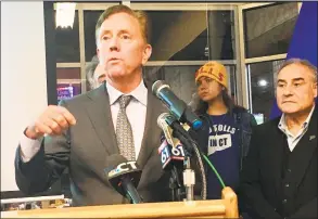  ?? Dan Haar / Hearst Connecticu­t Media ?? Gov. Ned Lamont presented his updated transporta­tion plan at the offices of reSET, a business incubator in Hartford, on Thursday. At center is Hilary Gunn, an antitolls protester from Greenwich and at right is Sal Luciano, president of the Connecticu­t AFLCIO, a tolls supporter.