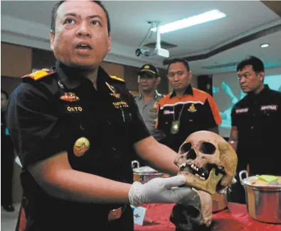  ??  ?? Customs officers with suspected Dayak skulls seized at an Indonesian airport, some of which were destined for Australia.